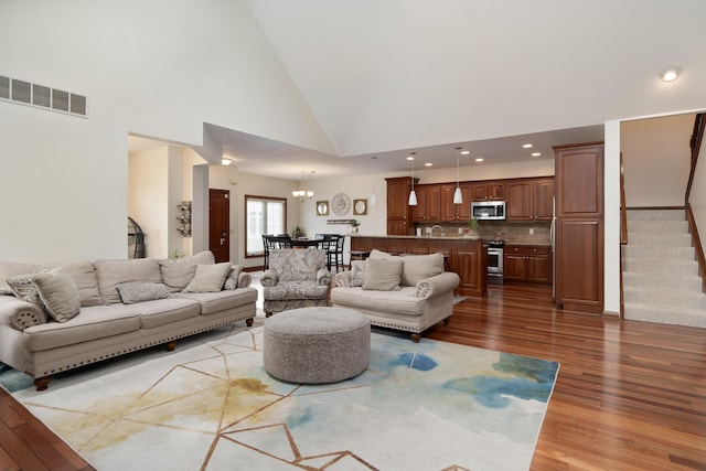 9785 Kingston Cir, Powell, OH 43065 - living room with wood finished floors, high vaulted ceiling, a chandelier, stairs, and recessed lighting