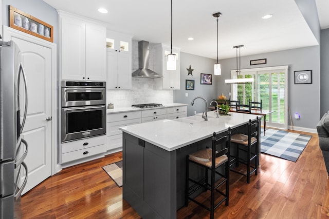 3687 Foresta Grand Dr, Powell, OH 43065 - kitchen with wall chimney range hood, stainless steel appliances, dark wood-style floors, tasteful backsplash, and white cabinets
