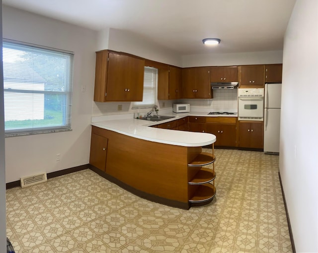 1616 Sale Rd, Columbus, OH 43224 - kitchen with white appliances, a sink, a peninsula, under cabinet range hood, and light countertops