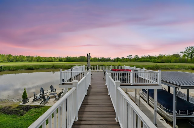 dock featuring a patio area, a water view, view of wooded area, and an outdoor fire pit
