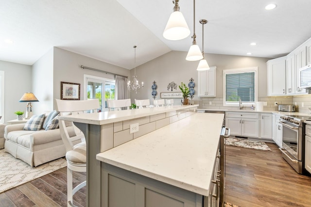 kitchen with electric range, dark wood finished floors, a breakfast bar area, a kitchen island, and backsplash