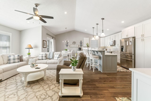 living room with lofted ceiling, dark wood-style floors, a ceiling fan, recessed lighting, and a chandelier