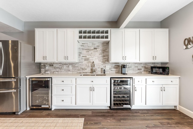 indoor wet bar featuring beverage cooler, freestanding refrigerator, black microwave, and dark wood finished floors