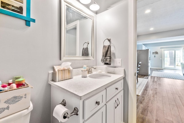 bathroom featuring toilet, vanity, wood finished floors, and recessed lighting