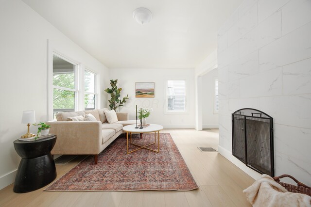 living room featuring wood finished floors, a tiled fireplace, and baseboards