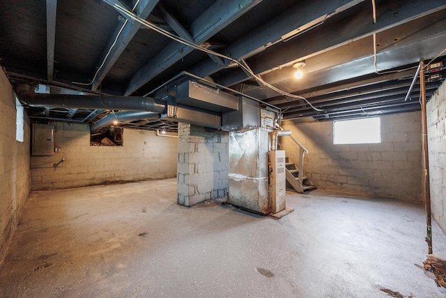 below grade area with electric panel, stairway, and heating unit