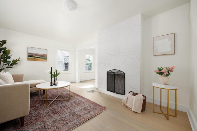 living area with wood finished floors, a high end fireplace, and baseboards