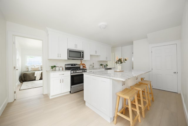 kitchen with appliances with stainless steel finishes, a center island, a kitchen breakfast bar, and white cabinetry
