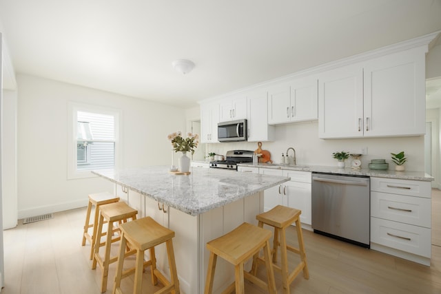 kitchen featuring stainless steel appliances, a breakfast bar area, a center island, and white cabinets