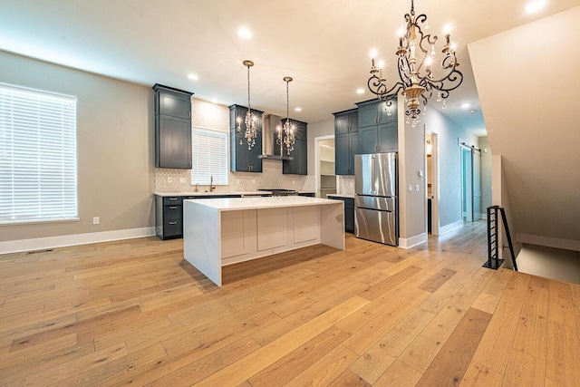 959 Hudson Xing, Columbus, OH 43212 - kitchen featuring freestanding refrigerator, a chandelier, wall chimney exhaust hood, light countertops, and backsplash