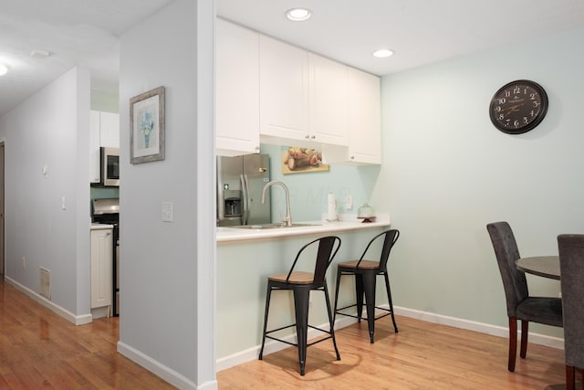 4618 Parrau Dr Unit 72B, Columbus, OH 43228 - kitchen featuring stainless steel appliances, a kitchen bar, white cabinets, light wood-style flooring, and recessed lighting