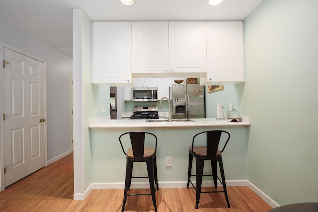 4618 Parrau Dr Unit 72B, Columbus, OH 43228 - kitchen featuring appliances with stainless steel finishes, a sink, light wood-style floors, a breakfast bar, and recessed lighting