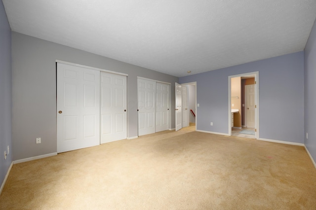 4618 Parrau Dr Unit 72B, Columbus, OH 43228 - unfurnished bedroom featuring two closets, baseboards, light carpet, and ensuite bath