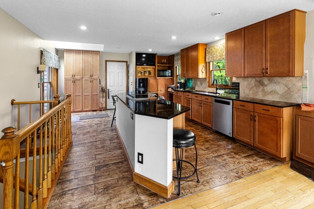251 Longbranch Dr, Dublin, OH 43017 - kitchen featuring stainless steel dishwasher, dark wood-type flooring, a sink, backsplash, and dark countertops