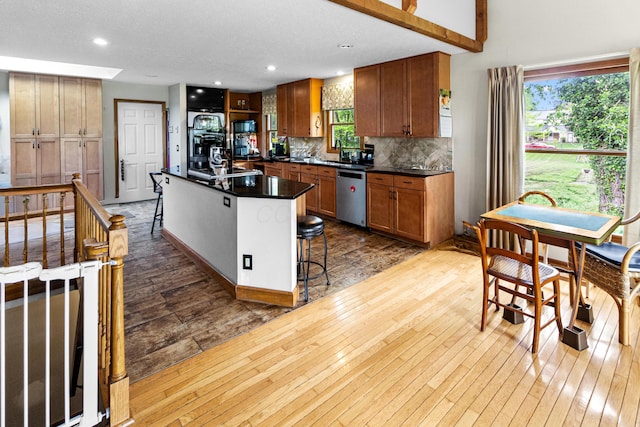 251 Longbranch Dr, Dublin, OH 43017 - kitchen with dishwasher, dark countertops, backsplash, a kitchen bar, and light wood-style floors