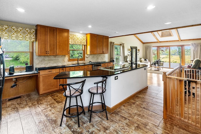251 Longbranch Dr, Dublin, OH 43017 - kitchen with brown cabinetry, dark countertops, decorative backsplash, a kitchen island, and light wood-style floors