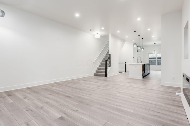 1177 Franklin Ave, Columbus, OH 43205 - unfurnished living room with stairway, recessed lighting, light wood-style flooring, baseboards, and a sink