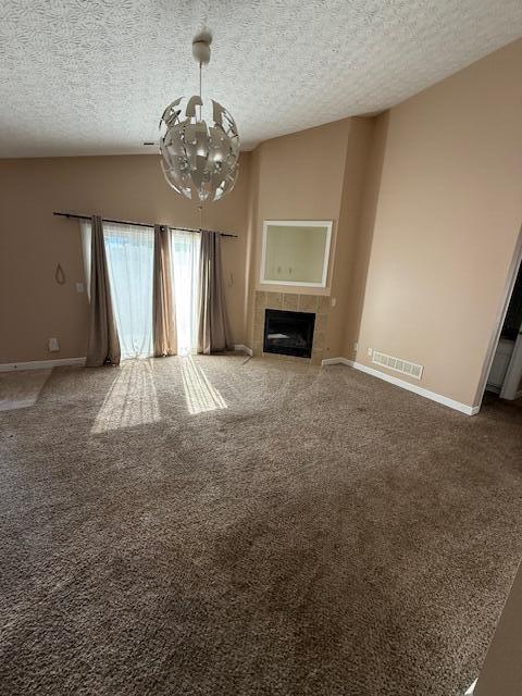 6983 Remsen Dr Unit 77A, Canal Winchester, OH 43110 - unfurnished living room with a chandelier, carpet, a textured ceiling, and a tile fireplace