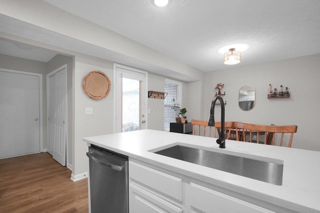 2999 Glenloch Cir, Dublin, OH 43017 - kitchen with stainless steel dishwasher, a sink, light countertops, light wood finished floors, and a textured ceiling