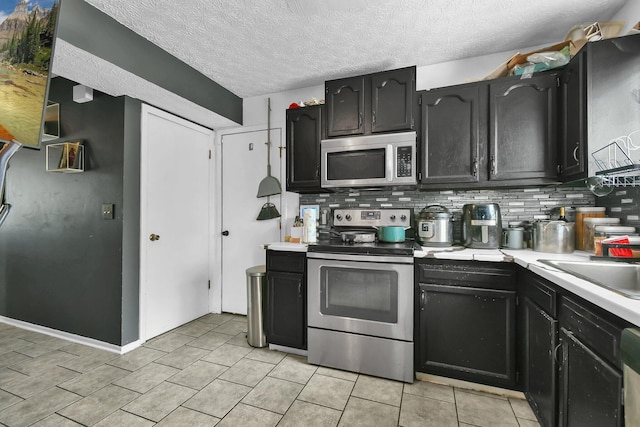 3072 Bocastle Ct, Reynoldsburg, OH 43068 - kitchen with stainless steel appliances, decorative backsplash, light countertops, a textured ceiling, and light tile patterned floors