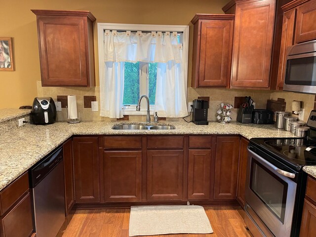 7719 Bear Run Rd, Logan, OH 43138 - kitchen with stainless steel appliances, a sink, light wood finished floors, and tasteful backsplash