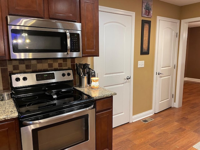 7719 Bear Run Rd, Logan, OH 43138 - kitchen with appliances with stainless steel finishes, light wood finished floors, baseboards, and decorative backsplash
