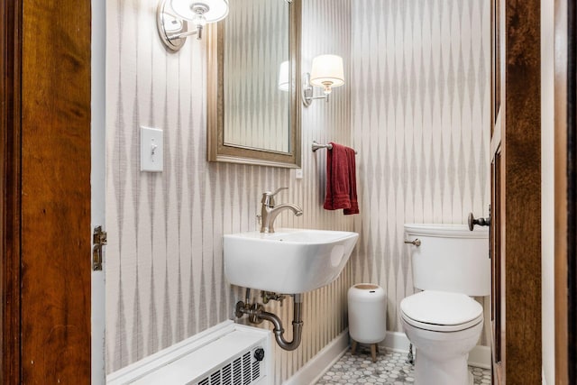 bathroom with wallpapered walls, toilet, a sink, tile patterned flooring, and baseboards
