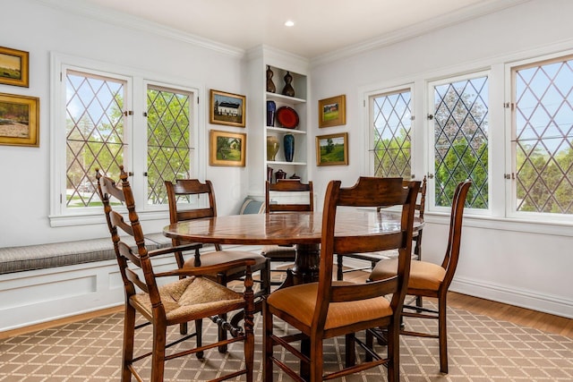 dining room featuring plenty of natural light, light wood-style flooring, crown molding, and baseboards