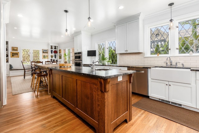 kitchen with stainless steel appliances, a sink, plenty of natural light, recessed lighting, and ornamental molding