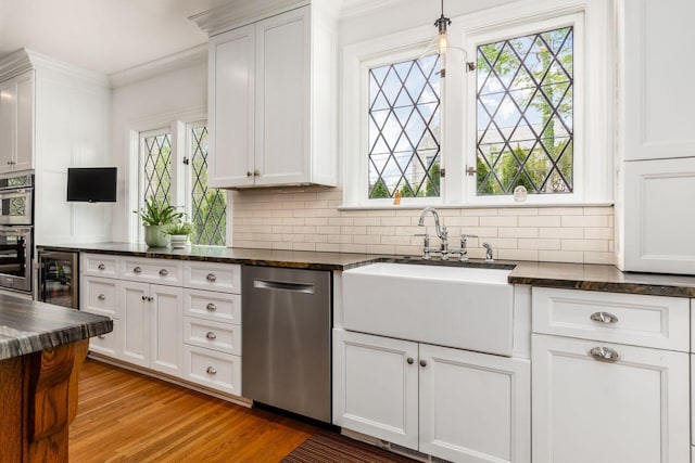 kitchen with appliances with stainless steel finishes, a sink, beverage cooler, healthy amount of natural light, and ornamental molding