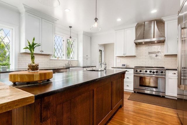 kitchen featuring stainless steel range, wall chimney exhaust hood, a sink, backsplash, and crown molding