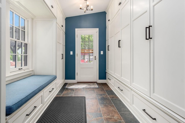 mudroom featuring baseboards, stone tile flooring, and a chandelier