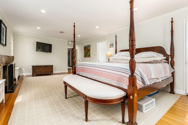 bedroom with light wood-style flooring, recessed lighting, baseboards, crown molding, and a fireplace