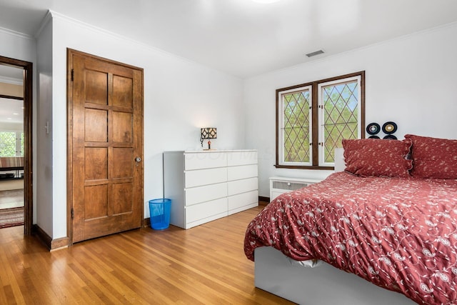 bedroom featuring wood finished floors, ornamental molding, and baseboards