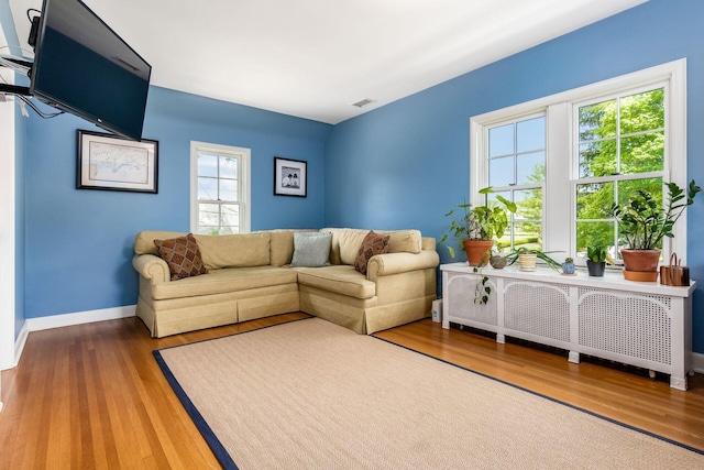 living room with radiator, wood finished floors, and baseboards