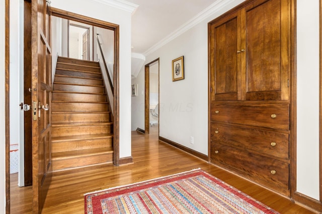 stairway featuring crown molding, wood finished floors, and baseboards