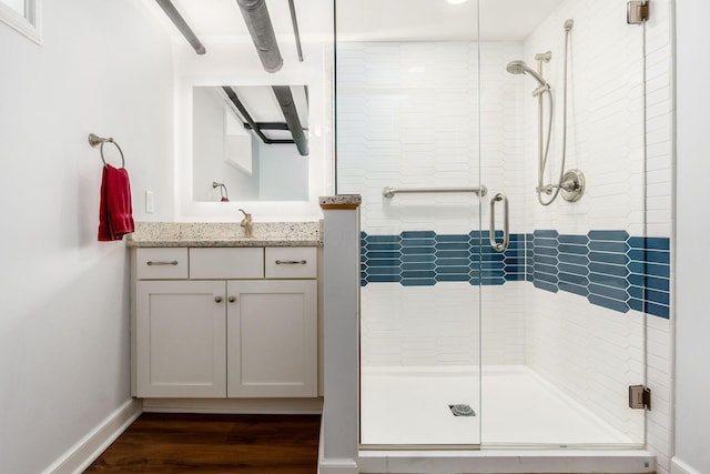 bathroom with a shower stall, wood finished floors, baseboards, and vanity
