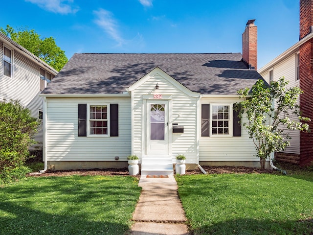 view of front of property featuring entry steps, a shingled roof, and a front yard