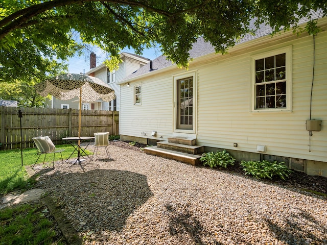 back of property featuring fence, entry steps, and roof with shingles