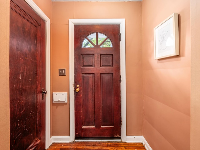doorway featuring baseboards and wood finished floors
