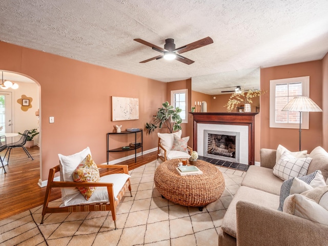 living area featuring arched walkways, plenty of natural light, a textured ceiling, and a ceiling fan