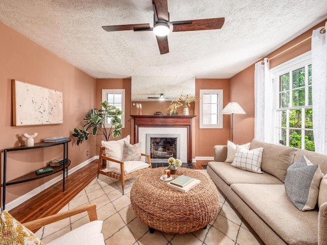living room with ceiling fan, healthy amount of natural light, a textured ceiling, tile patterned floors, and baseboards