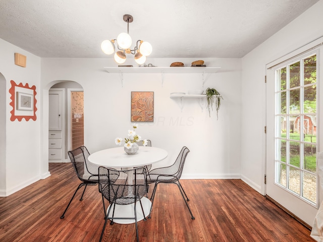 dining area with arched walkways, a chandelier, wood finished floors, and baseboards