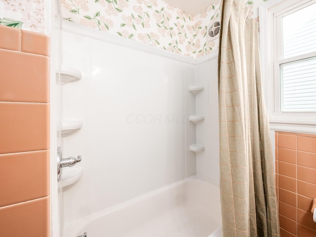 bathroom with wallpapered walls, a wainscoted wall, and shower / bath combo