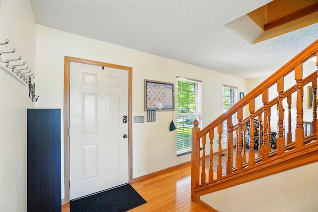 8380 Squad Dr, Galloway, OH 43119 - entryway featuring light wood-style flooring, stairs, a textured ceiling, and baseboards