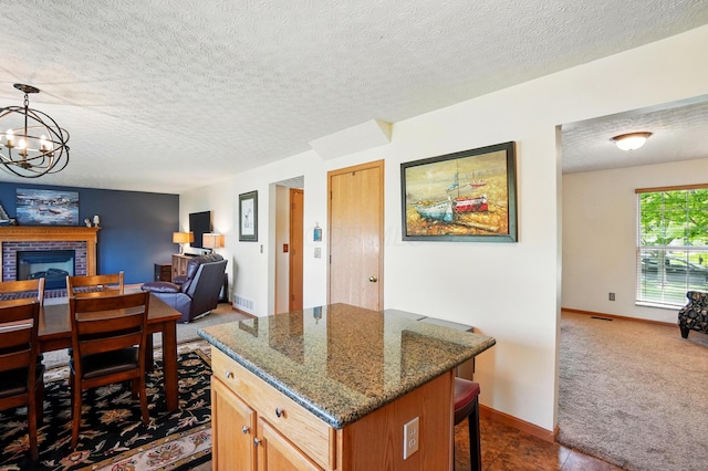 8380 Squad Dr, Galloway, OH 43119 - kitchen with open floor plan, a kitchen bar, a kitchen island, dark stone counters, and a brick fireplace