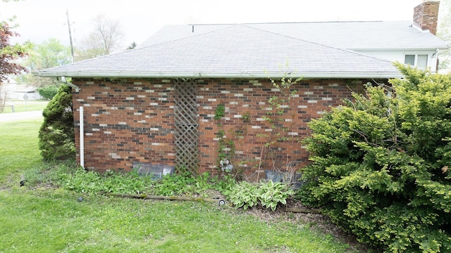 view of property exterior featuring a chimney, a lawn, and brick siding