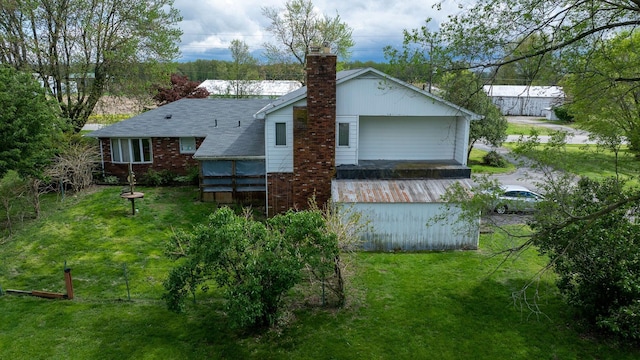 rear view of house featuring a chimney, a lawn, brick siding, and a shingled roof