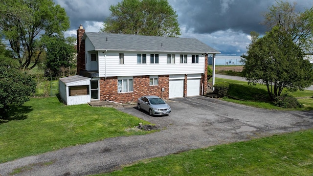 view of front of property featuring driveway, a chimney, brick siding, and a front lawn