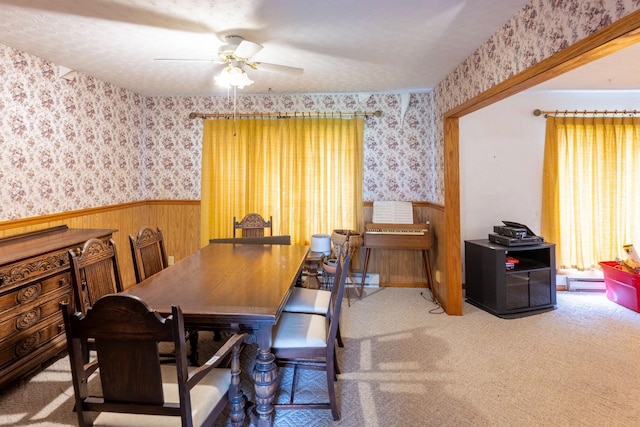 dining area with wallpapered walls, wainscoting, ceiling fan, a baseboard heating unit, and carpet